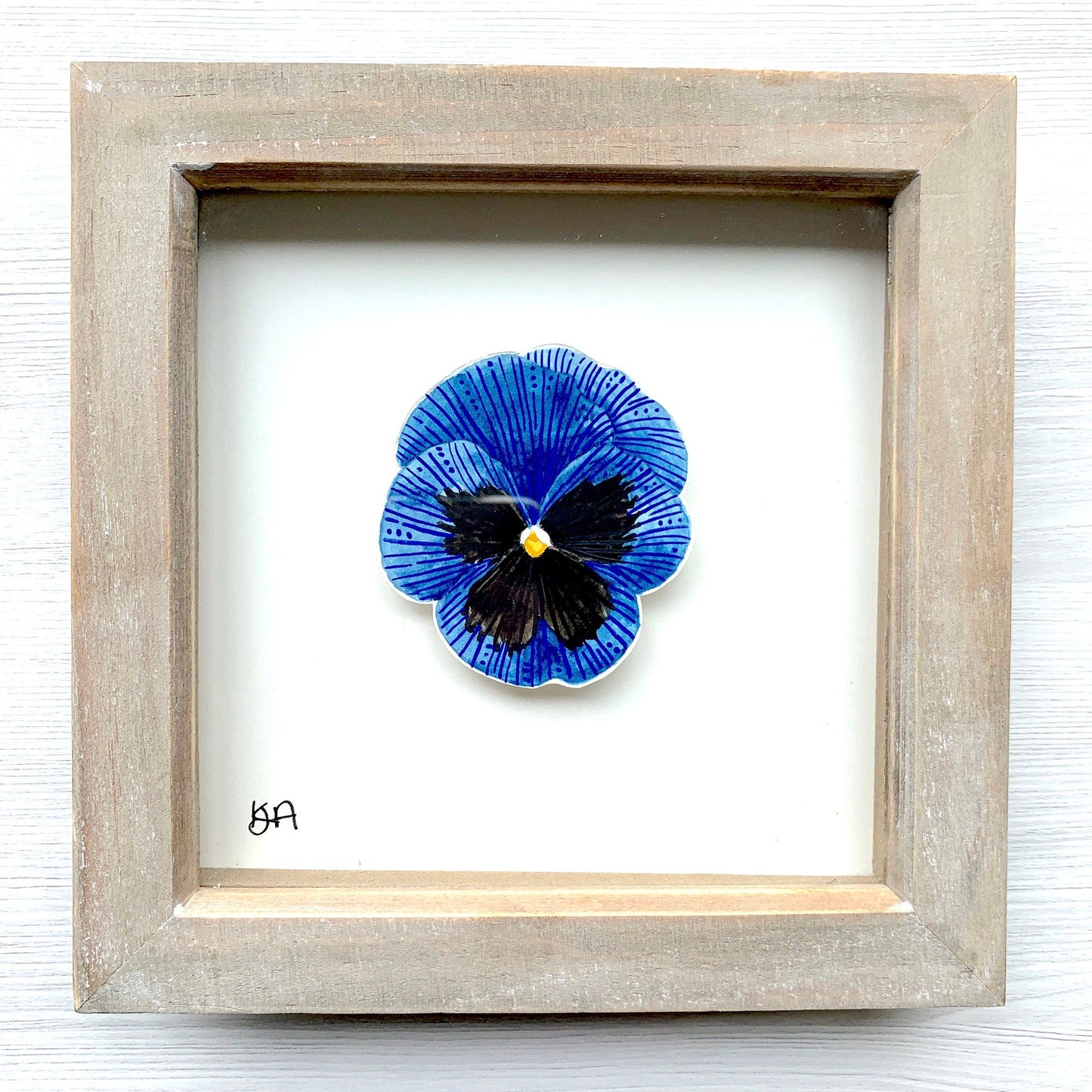 A hand-painted watercolor and gouache painting of a blue and black pansy flower, framed in a rustic washed effect frame.