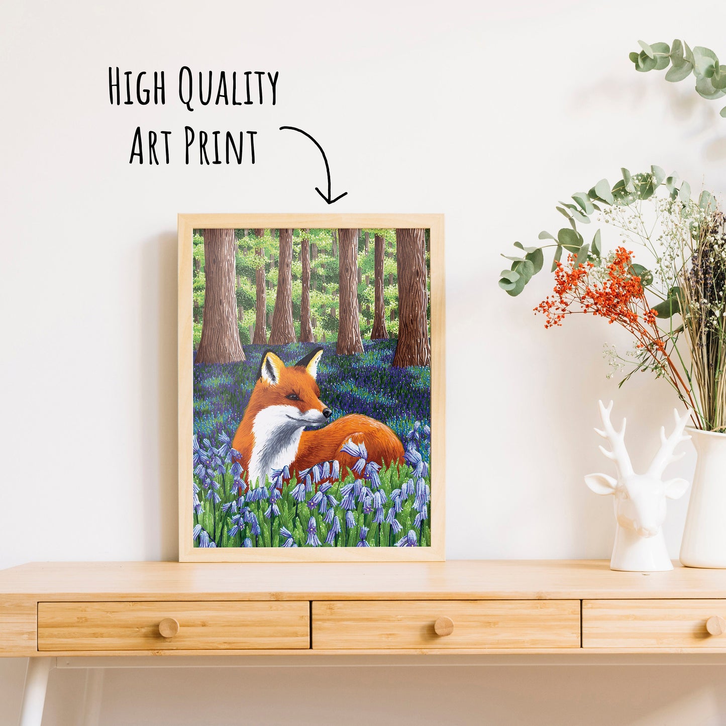 an art print of a fox laying amongst the bluebells in a woodland. placed in a wooden frame.