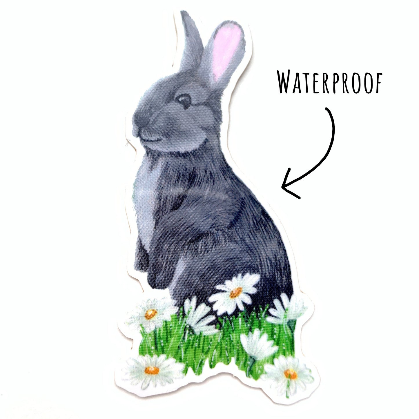 Little Wild Rabbit and Daisies Sticker laying flat on a white surface with the text waterproof.