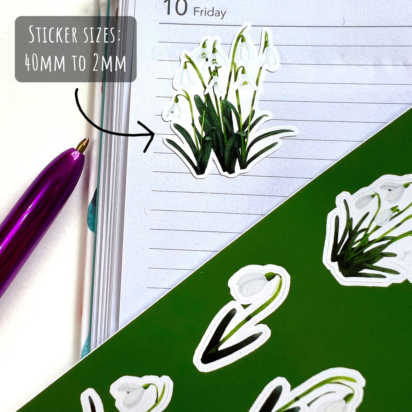 showing one of the stickers from Snowdrop Flower Sticker Sheet on a lined page of a diary with the text sticker sizes: 40mm to 2mm.