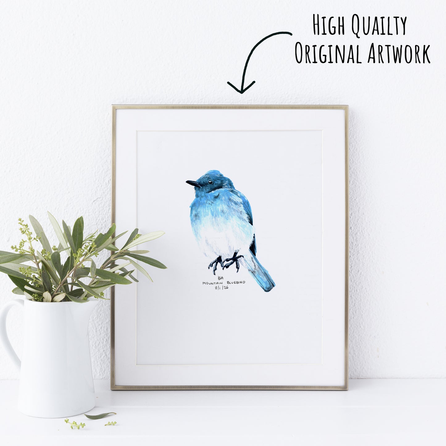 Framed artwork of a blue bird on a white wall with a plant to the left.