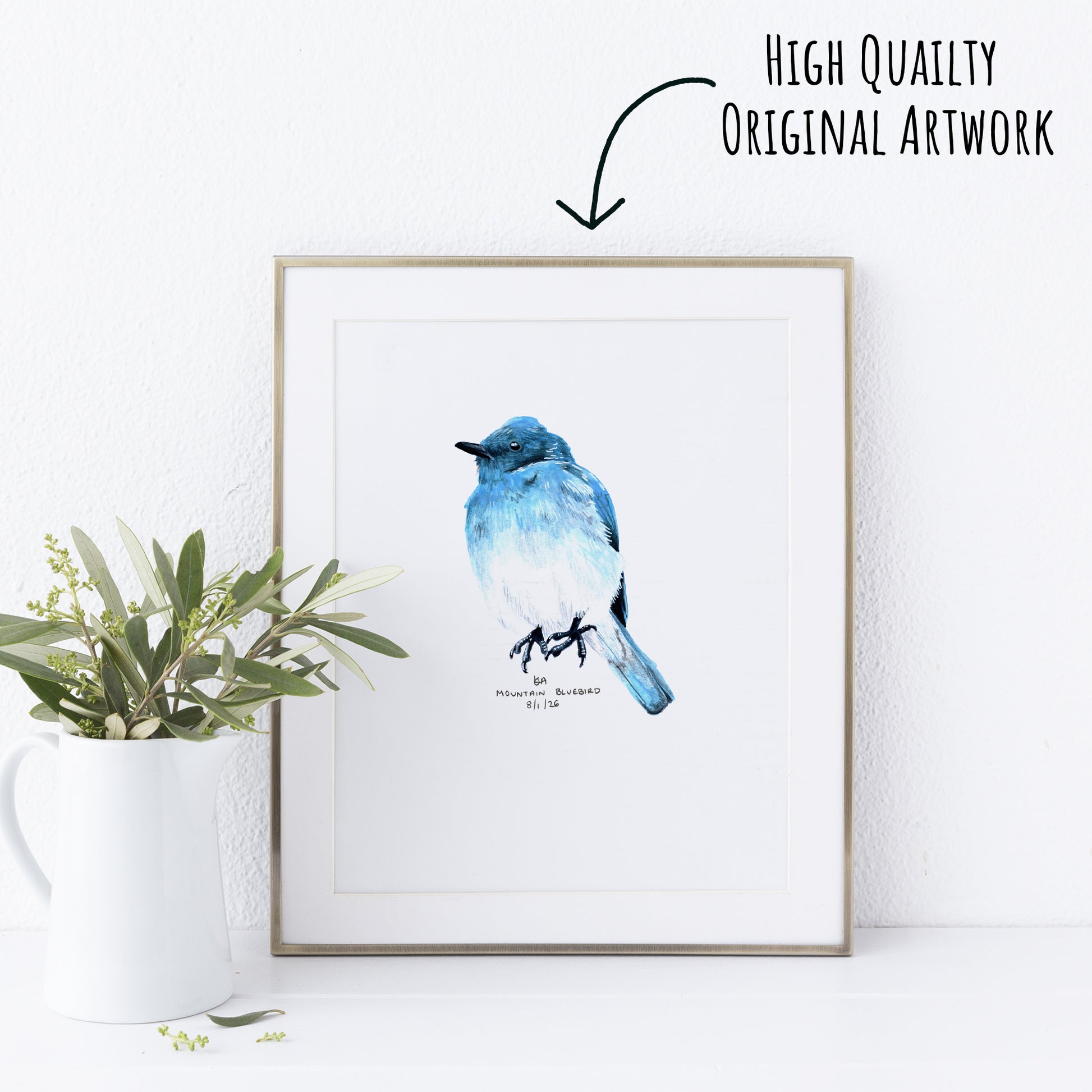 Framed artwork of a blue bird on a white wall with a plant to the left.