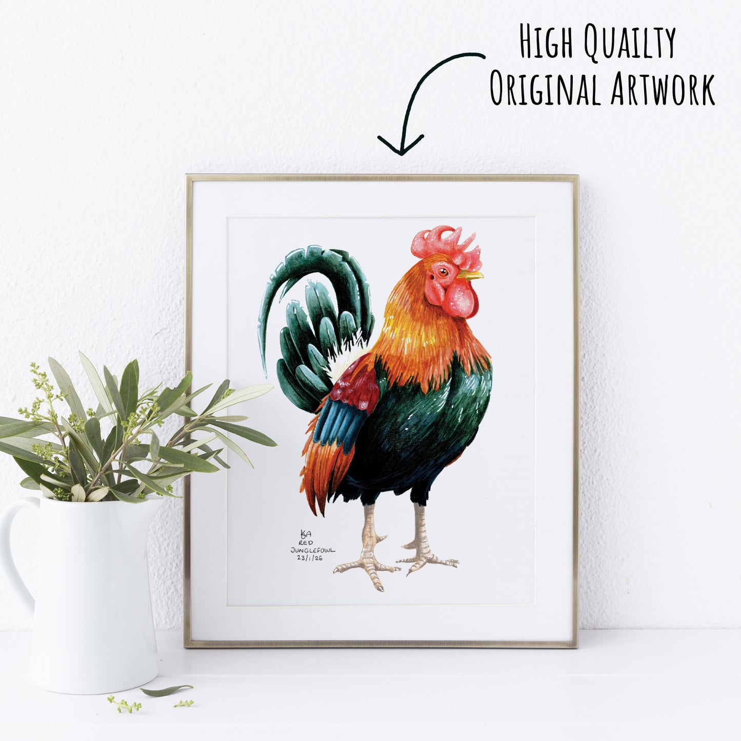 Framed artwork of a colourful rooster on a white wall with a plant to the left.