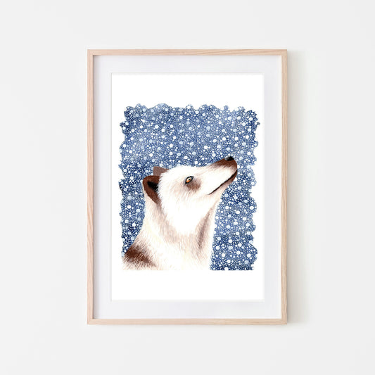 Art print of a white arctic fox with brown details on a dark blue snowy background, framed in a light wood frame.