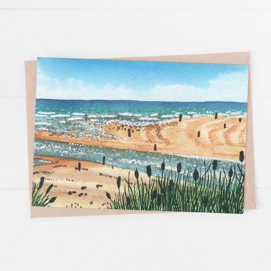 Beadnell Bay beach Birthday Card which is a painted scene of Beadnell bay in Northumberland. Laying on a white surface.