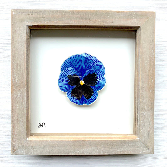 A hand-painted watercolor and gouache painting of a blue and black pansy flower, framed in a rustic washed effect frame.