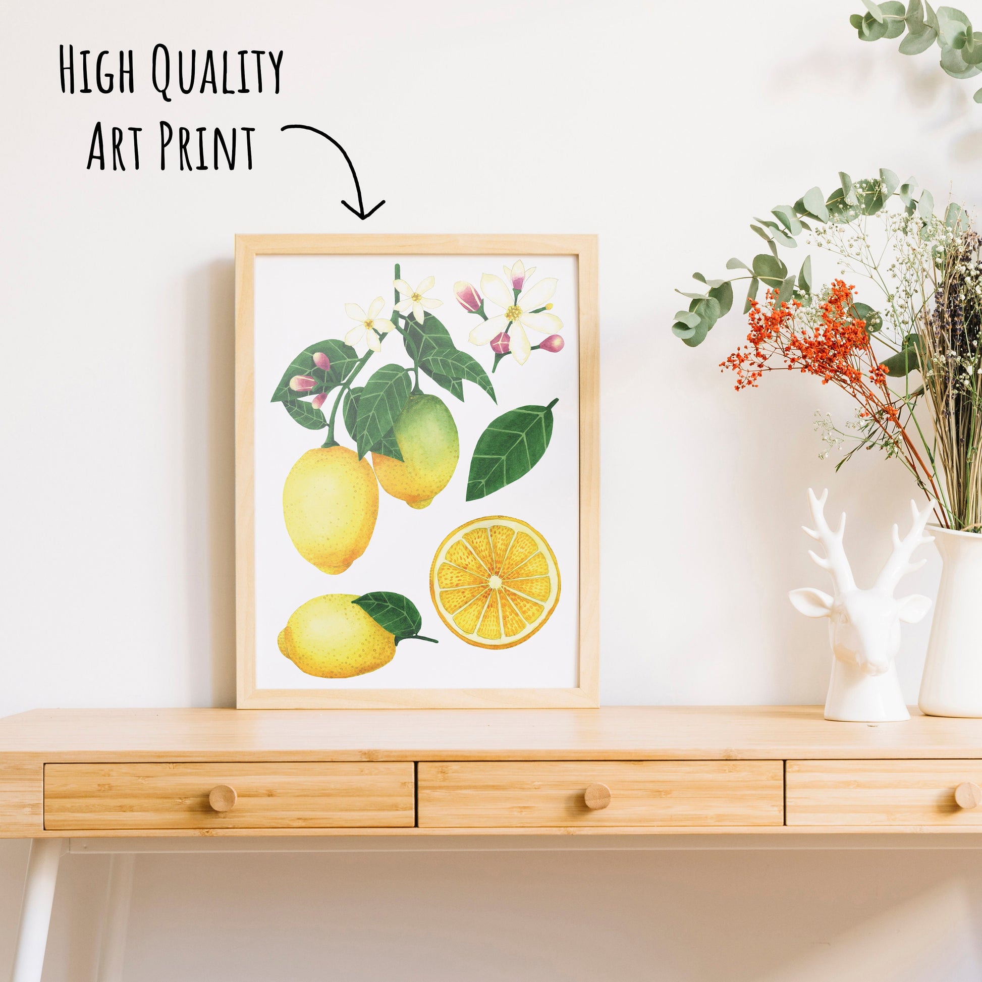 Botanical Lemon Art Print in a light wooden frame on a table top with a vase for dried foliage.