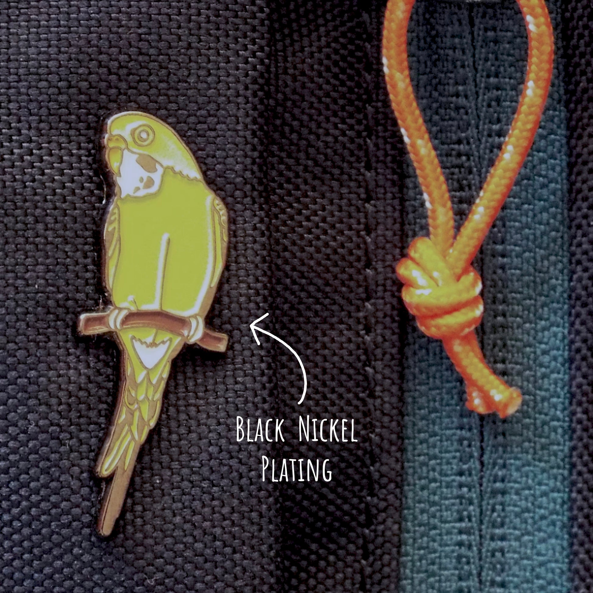 Budgie Enamel Pin Badge pinned to a bag with the text black nickel plating.