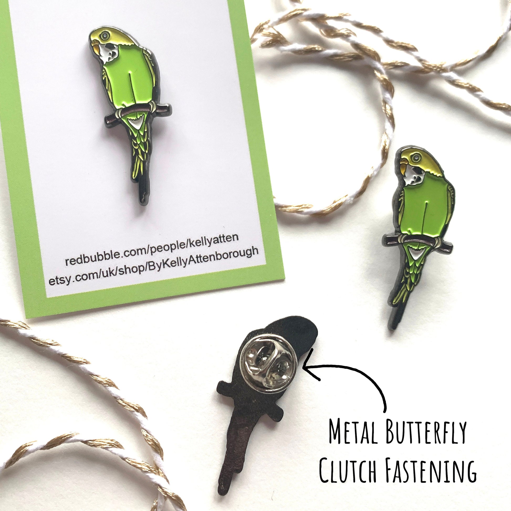 Showing three yellow and green Budgie Enamel Pin Badges. One on is backing card, one without and one showing the back with the metal butterfly clutch fastening. All on a white surface with the text metal butterfly clutch fastening.