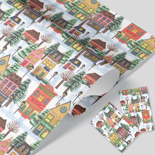 Christmas village wrapping paper with tags resting on a white surface.