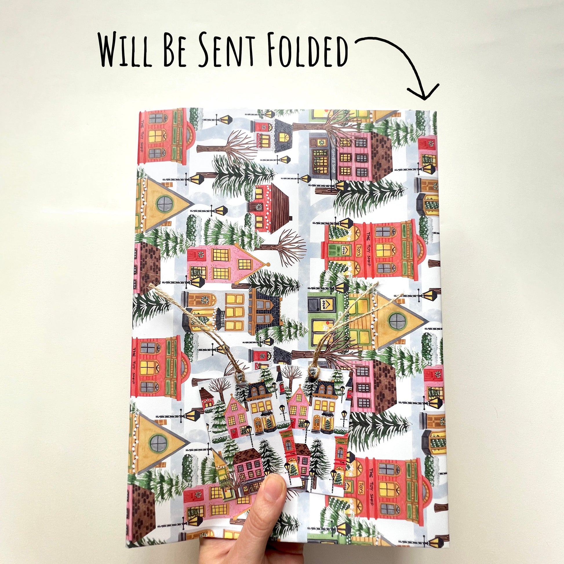 Showing that the Christmas Village Wrapping Paper will be folded to and A$ size for easier shipping. with the text will be sent folded.