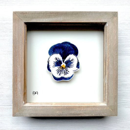 Framed artwork of a blue and white pansy on a white background