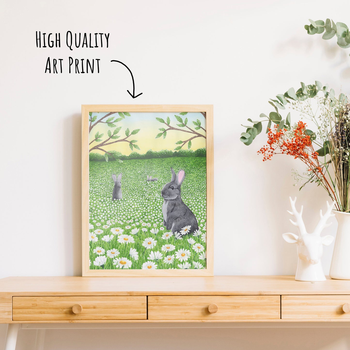 Floral Rabbit Art Print in a light wooden frame on a table top with a vase of dried foliage