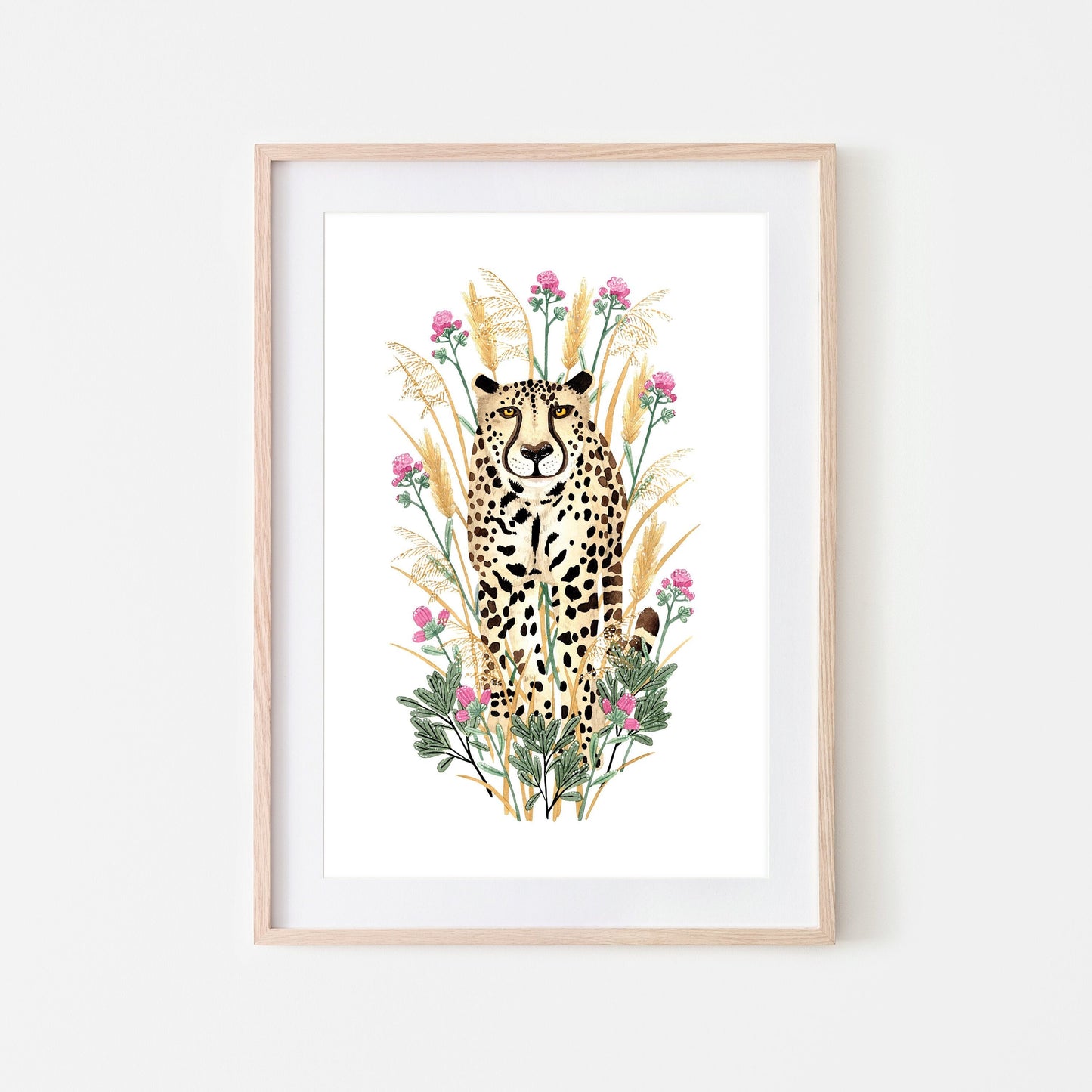 A framed artwork of a golden cheetah surrounded by grasses, flowers, and leaves.