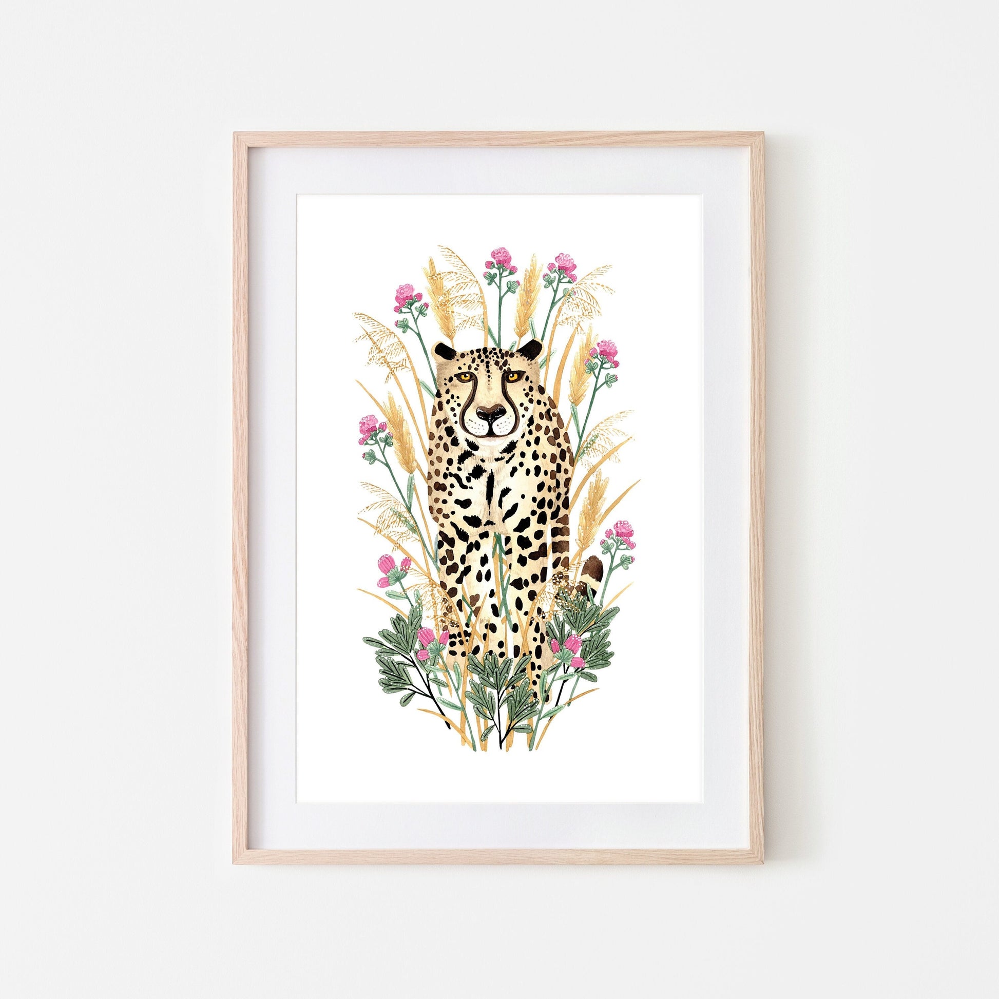 A framed artwork of a golden cheetah surrounded by grasses, flowers, and leaves.