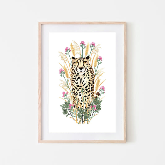 A framed artwork of a golden cheetah surrounded by grasses, flowers, and leaves.