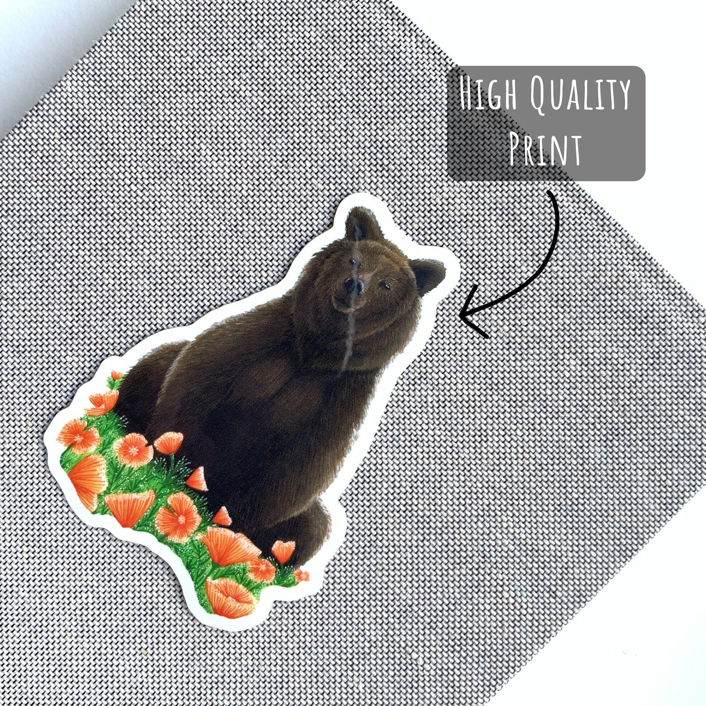 Grizzly Bear and Poppies Vinyl Sticker laying flat (stuck) on the front cover of a notebook.