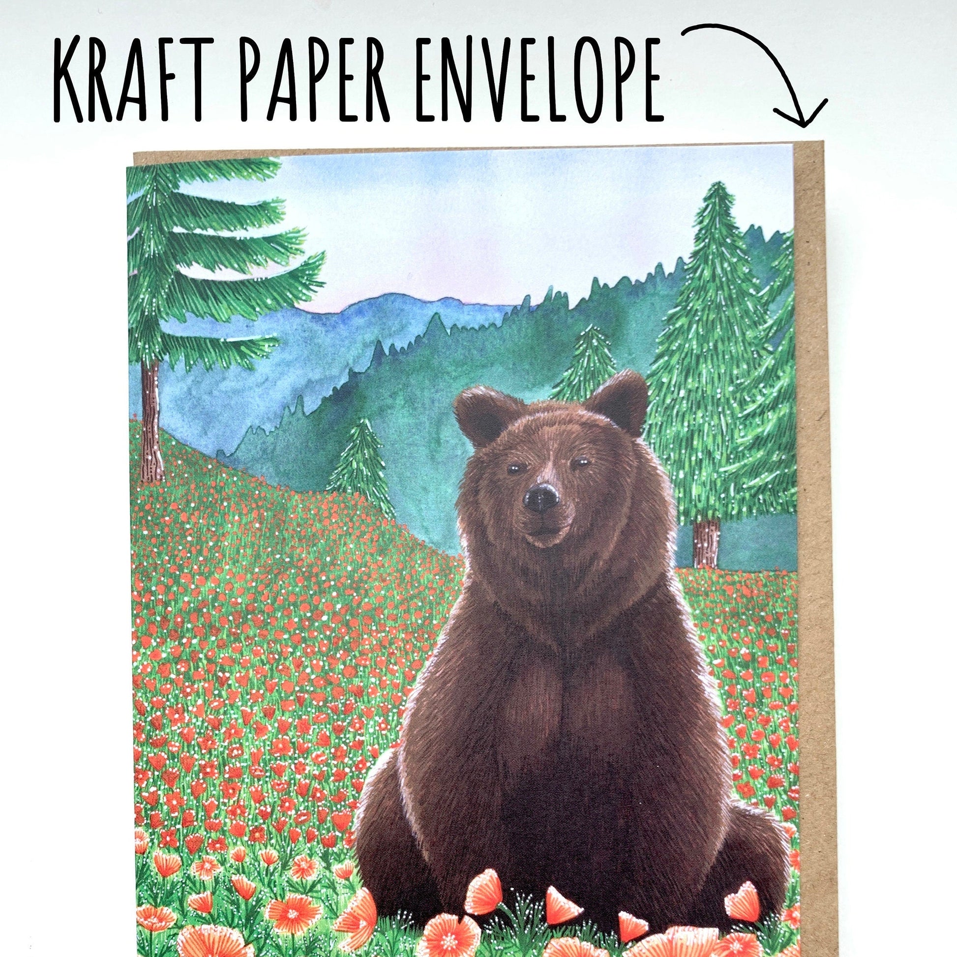 Kraft paper envelope with a bear illustration on a card held by a hand against a white surface. with text kraft paper envelope.