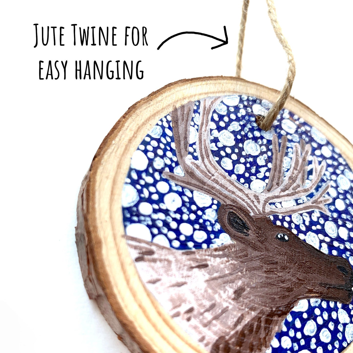 Hand Painted Reindeer Wood Slice Ornament close up showing the details of the illustration with the text: jute twine for easy hanging.