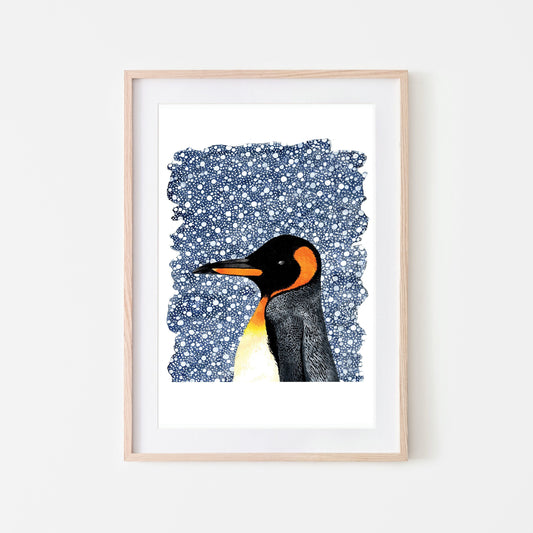 A watercolor art print of a king penguin with a snowy background, framed in a light wood frame.