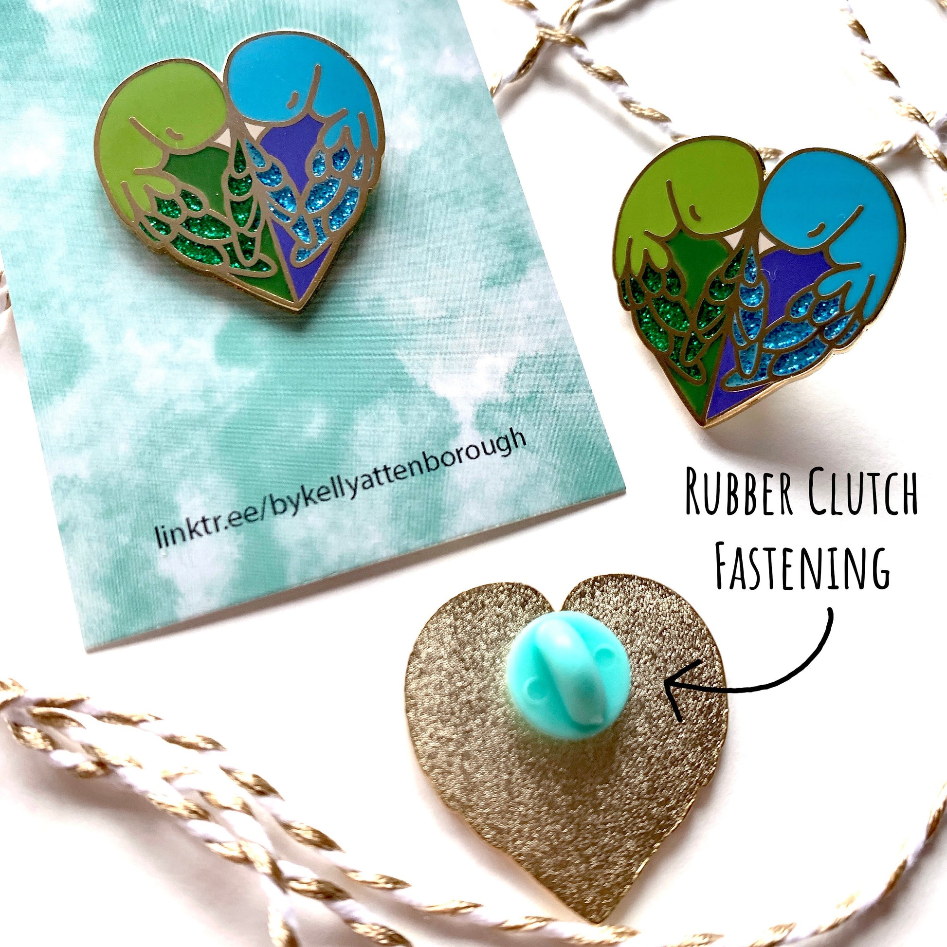 Showing three of the Love Birds Enamel Pin badges. One with its backing card, one with out and the third one showing the back with its mint coloured rubber clutch fastening. All place on a white surface with the text Rubber clutch fastening.