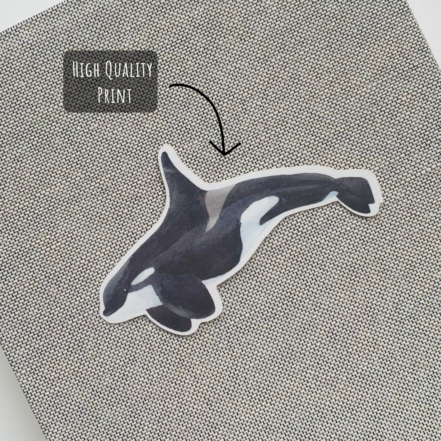 Orca Whale Sticker placed on the front on a grey notebook with the text high quality print.