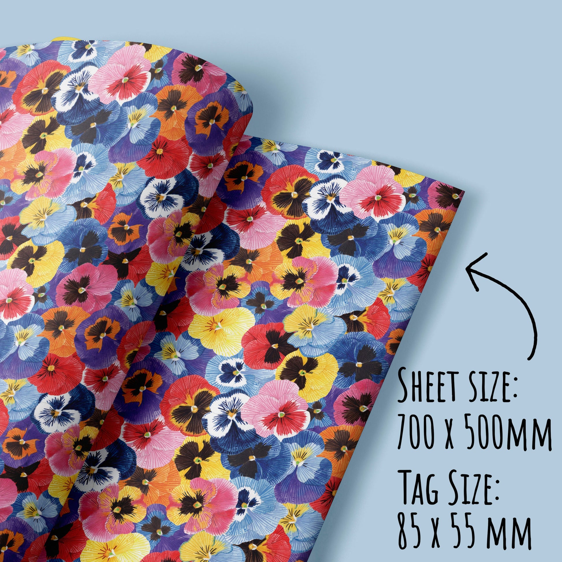 Pansy Flower Wrapping Paper folded on a light blue surface with the text sheet size: 700 x 500mm and tag size: 85 x 55mm.