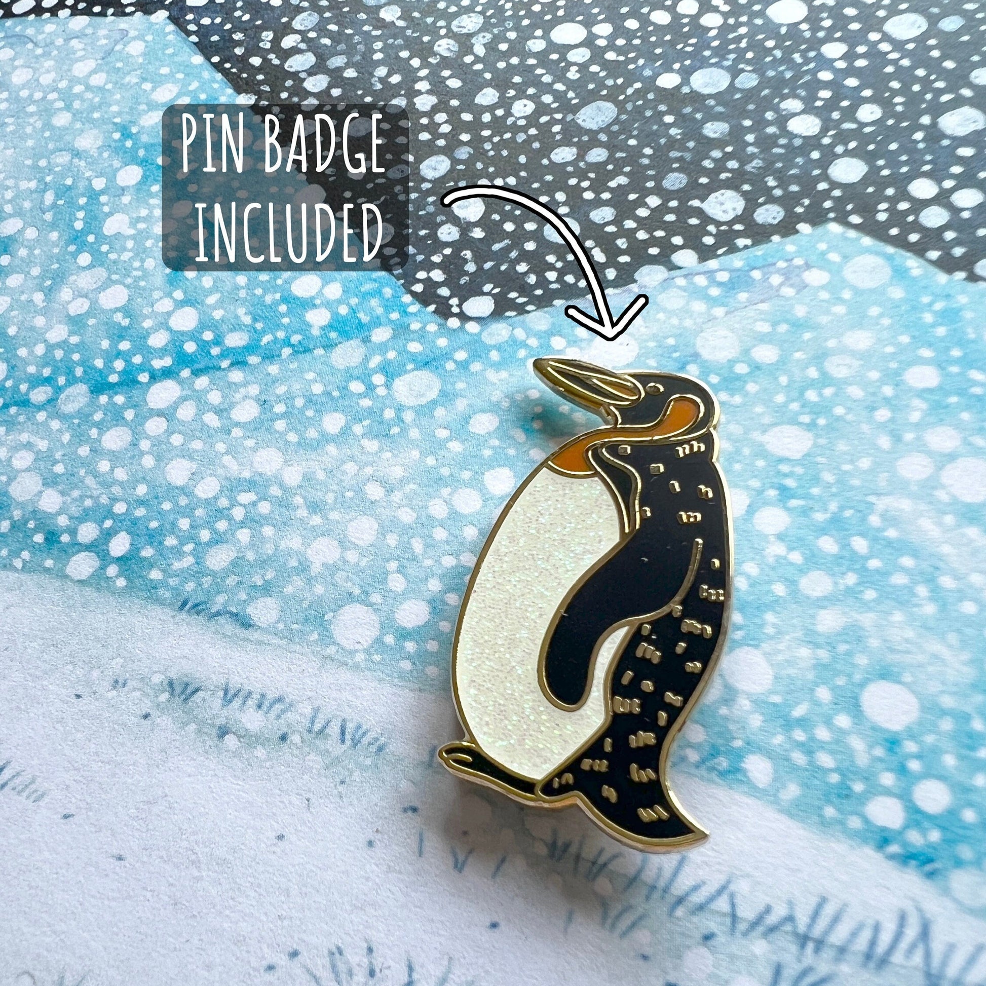 Penguin pin badge on a snowy background with text indicating 'Pin Badge Included' and '350GSM Smooth Finish'.