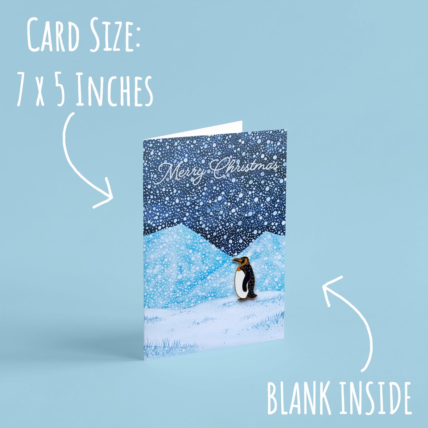 Penguin Enamel Pin with Christmas Card standing with a light blue backgournd with the font card size: 7 x 5 inches and blank inside.