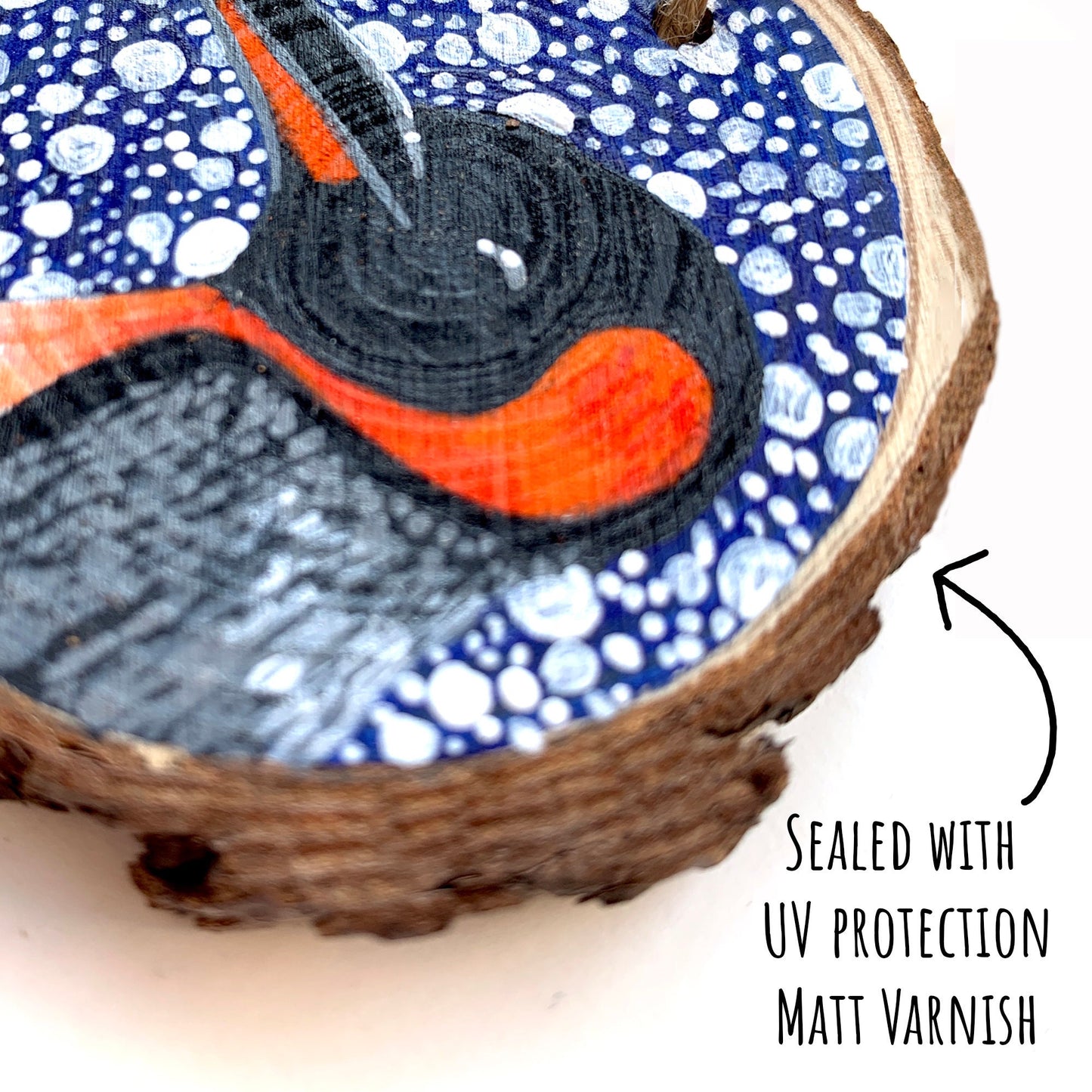 Penguin Wood Slice Ornament close up showing the details of the painted illustration with the text: sealed with uv protection matt varnish.