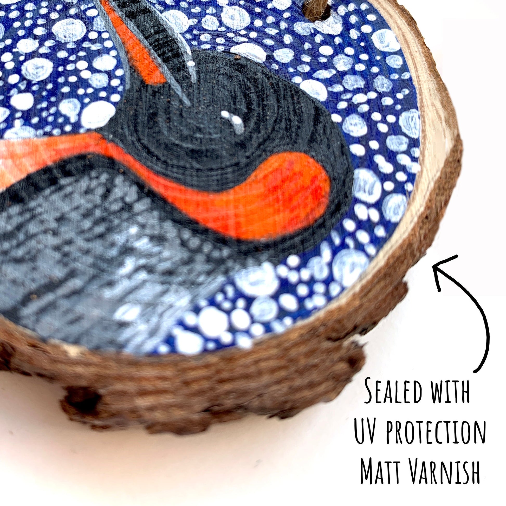 Penguin Wood Slice Ornament close up showing the details of the painted illustration with the text: sealed with uv protection matt varnish.
