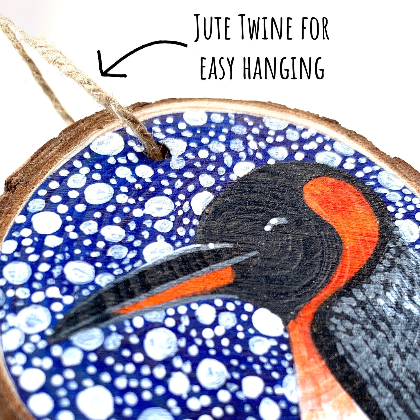 Penguin Wood Slice Ornament close up showing the details of the painted illustration with the text: jute twine for easy hanging. 