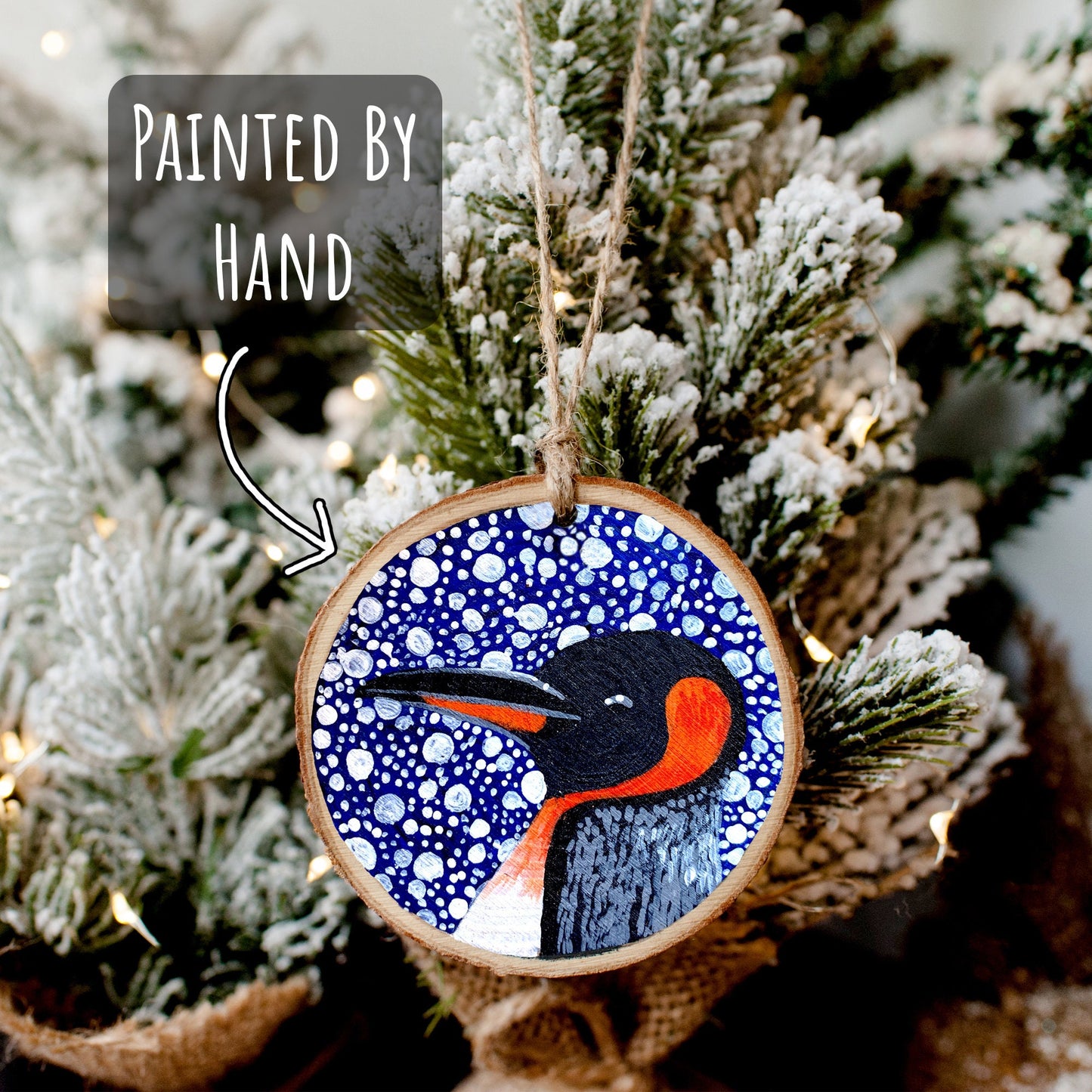 Penguin Wood Slice Ornament hanging from a mini christmas tree with the text painted by hand.