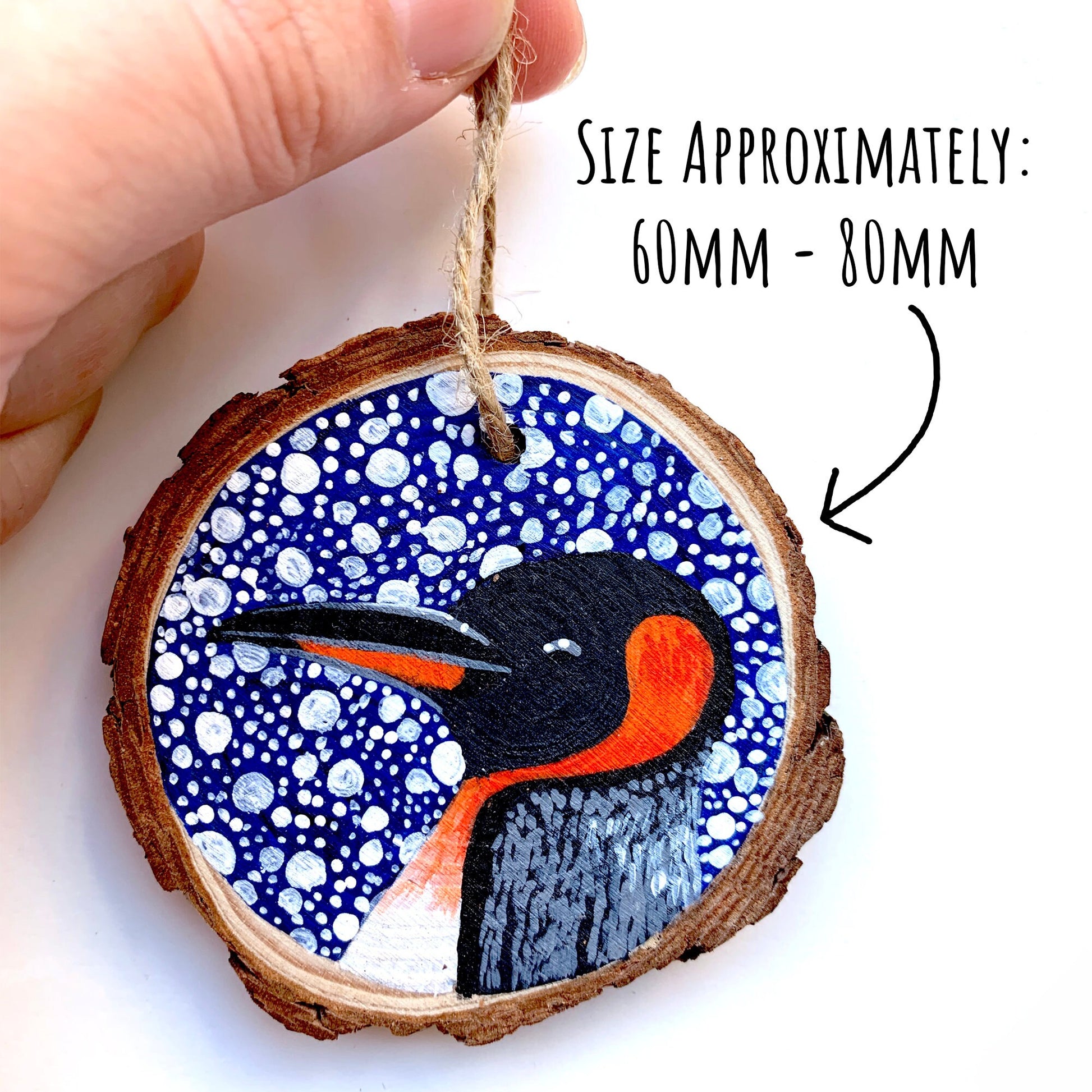 Penguin Wood Slice Ornament being held up agains a white background with the text: size approximately 60mm - 80mm.