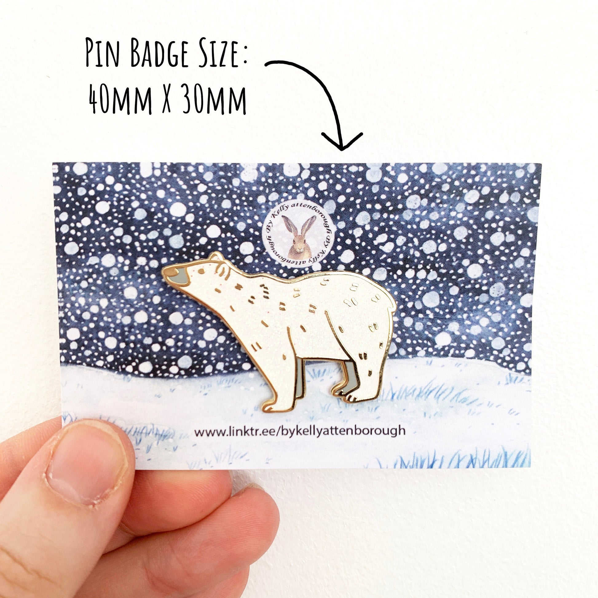 Polar Bear Enamel Pin badge on its snowy landscape backing card, being held up against a white background. With the text pin badge size: 40mm x 30mm.