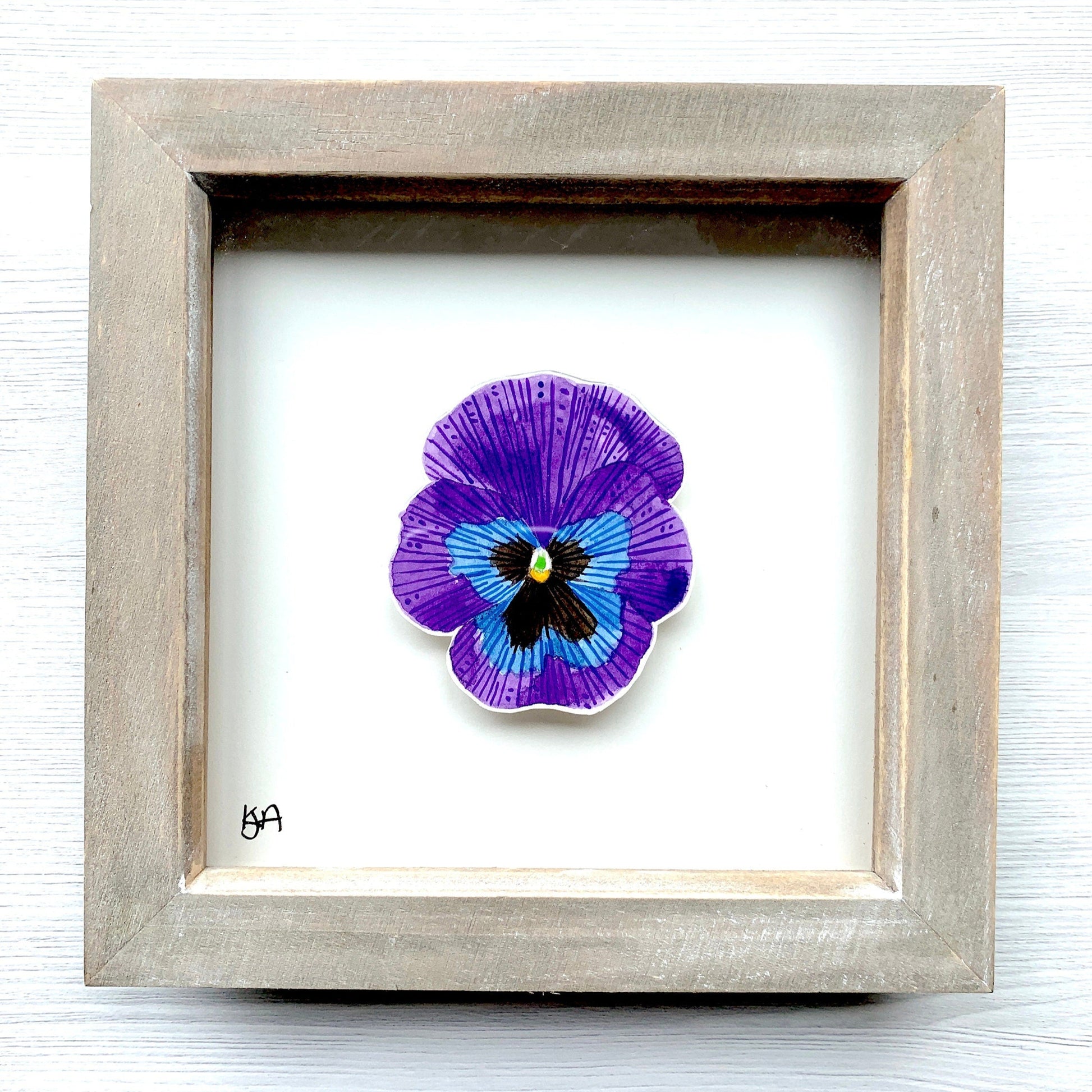 A hand-painted watercolor painting of a purple blue & black pansy flower, framed in a rustic washed effect frame.