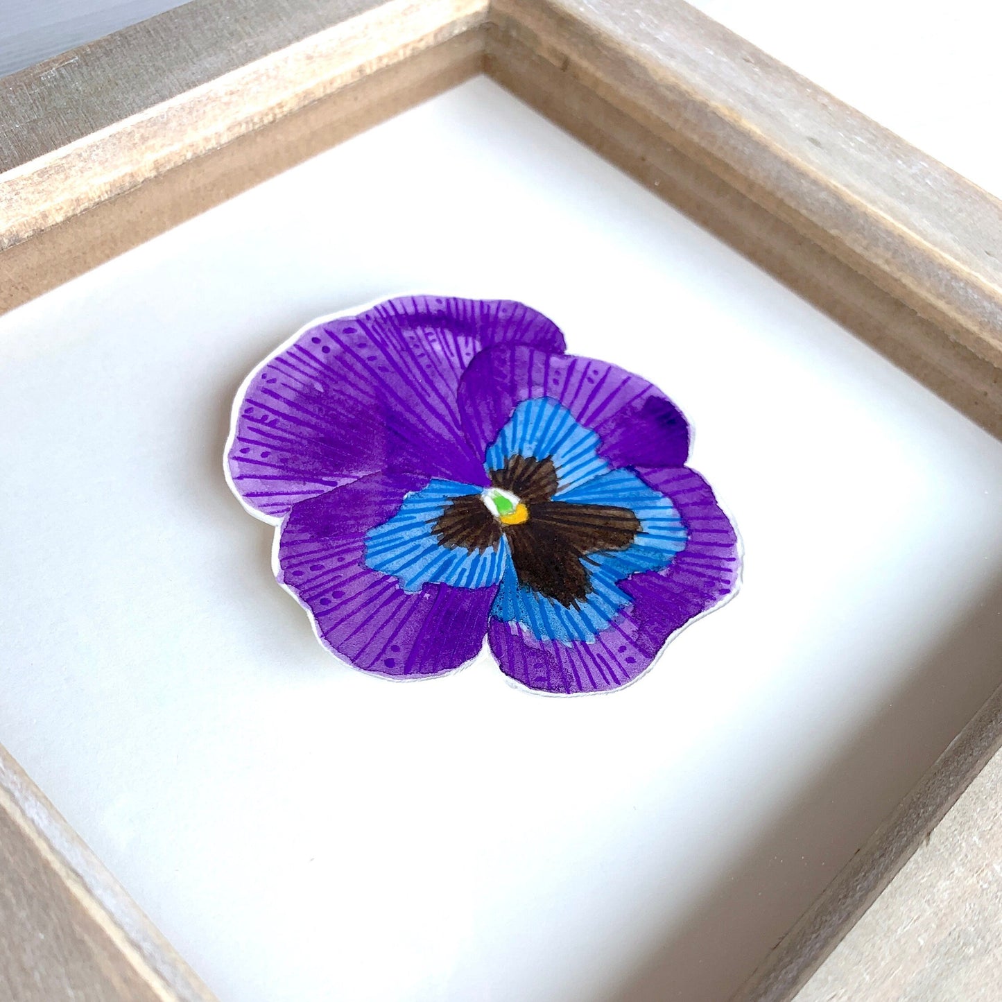 Framed artwork of a purple and blue flower with a white background