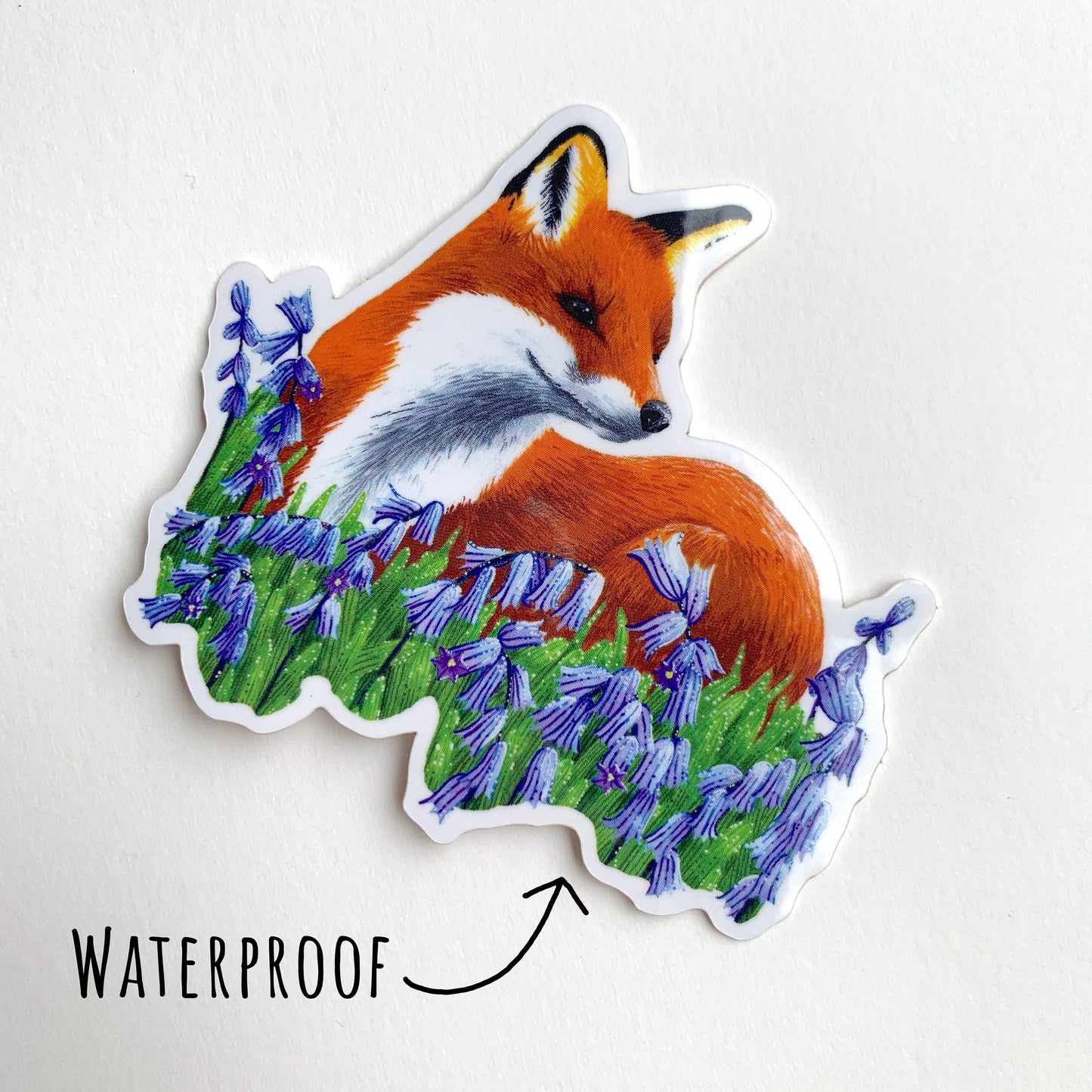 Red Fox and Bluebells Sticker laying flat on a white surface with the text waterproof.