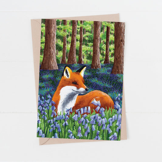Greeting card with a red fox in a bluebell woodland forest design on a white background.