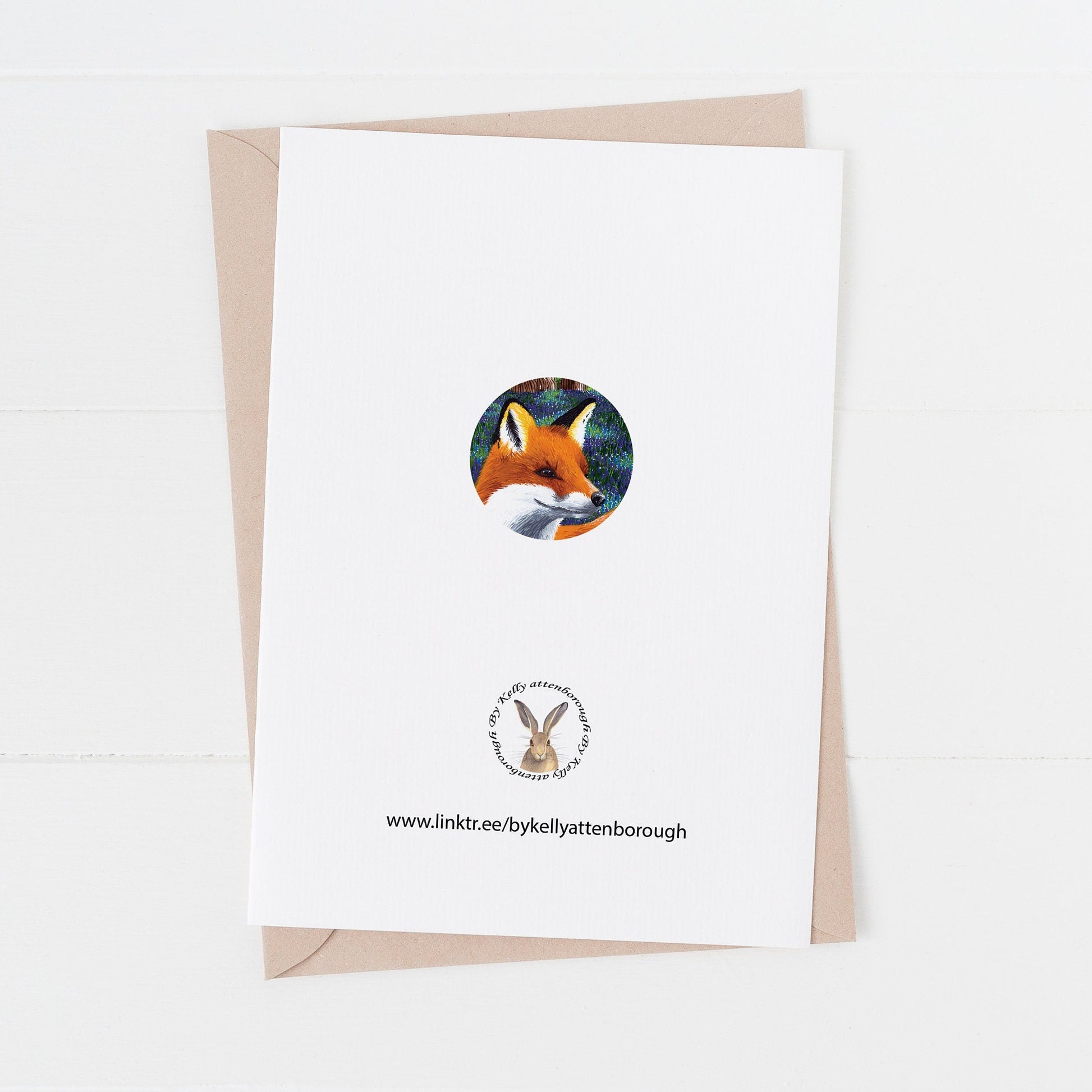 Red Fox with bluebells Birthday Card back with a small circle of a red fox. illustration with brand logo. card is on a white background.