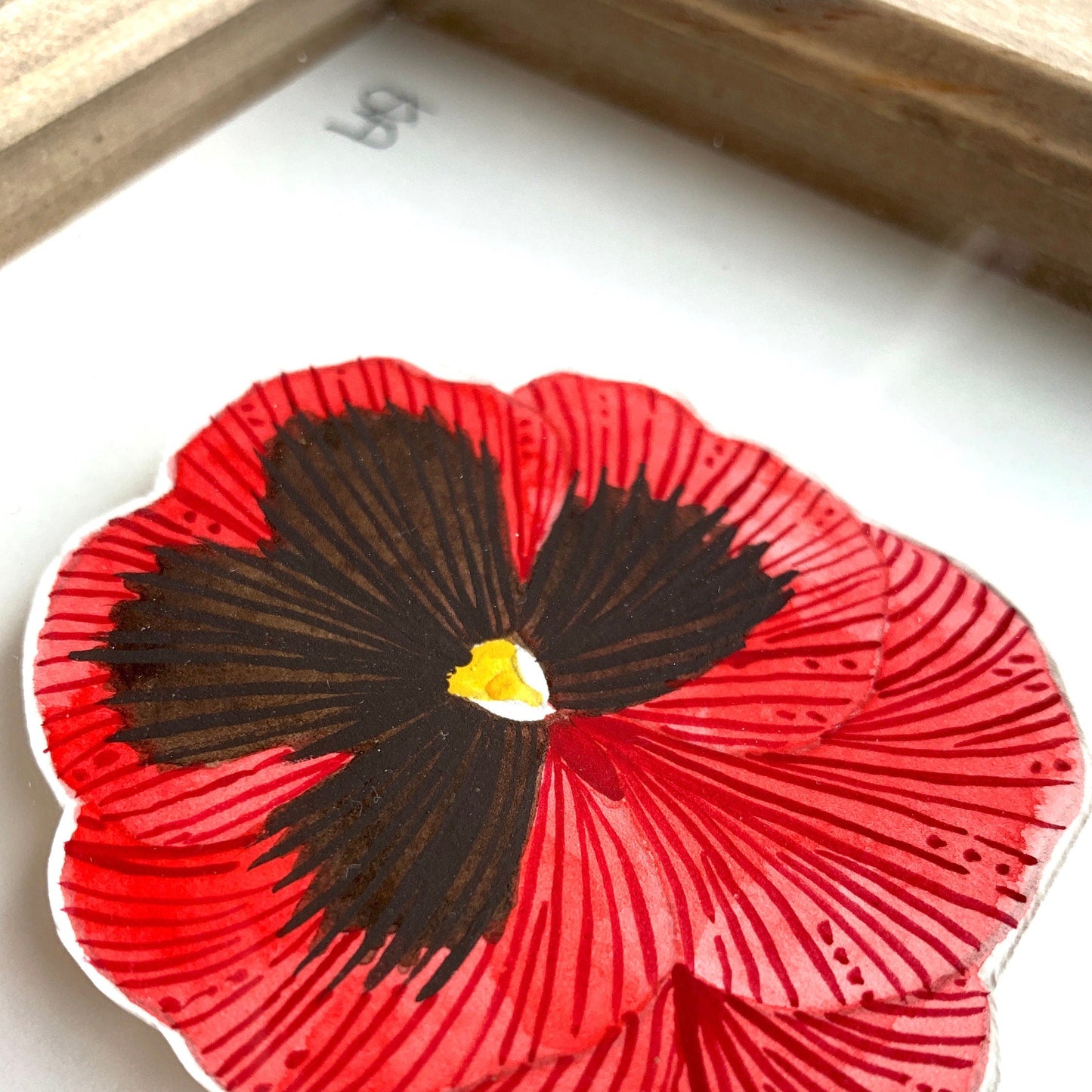Red and black pansy flower painting in rustic wooden frame. showing a close up