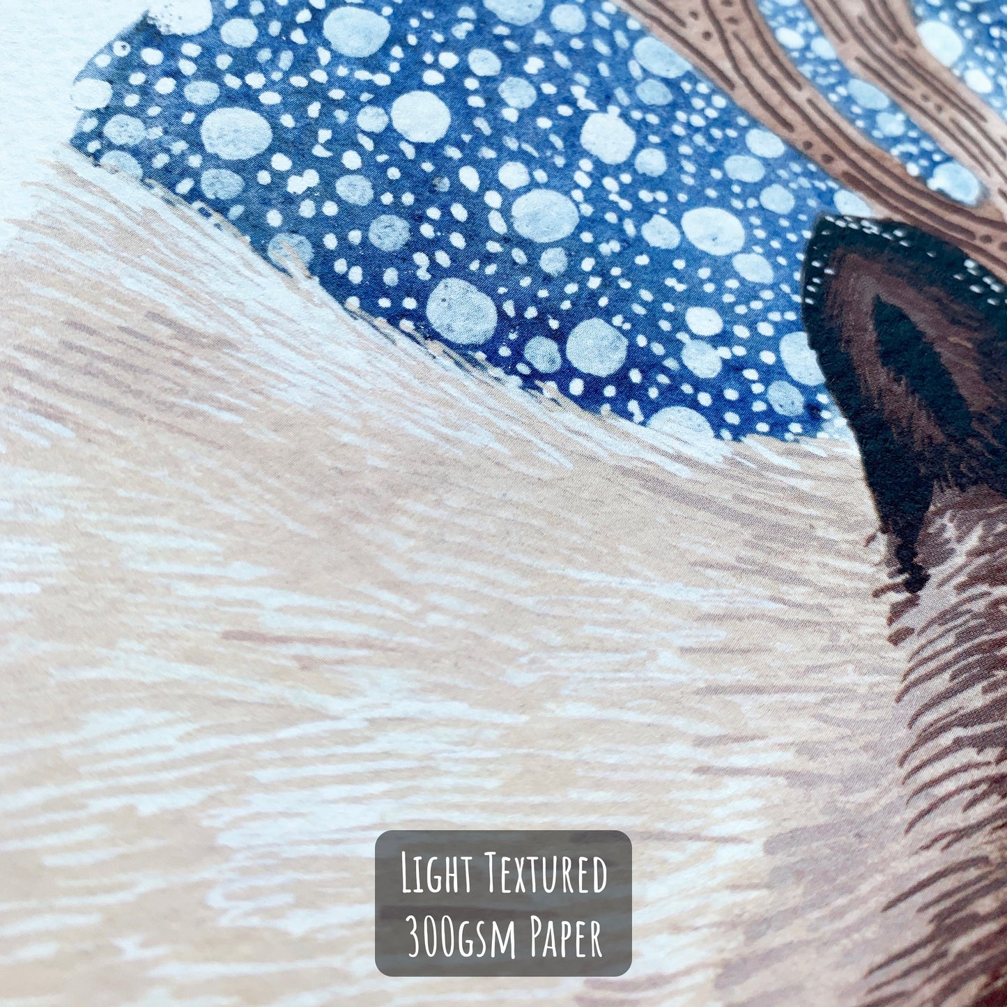 Reindeer art print with a dark blue snowy background close up showing the details and textures of the print and paper its on.