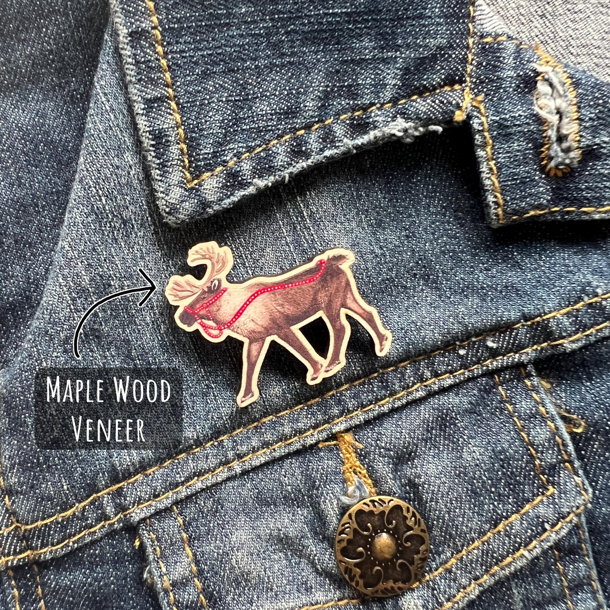 Reindeer Maple Wood Pin Badge being wore on a dark blue denim jacket, With text Maple wood veneer. 