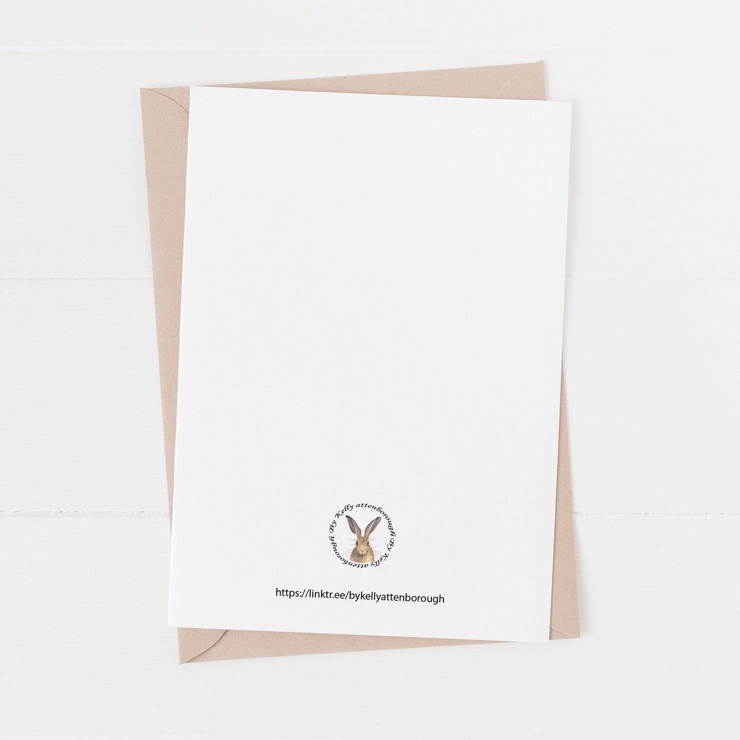 White card with a logo and text on a beige envelope against a white background