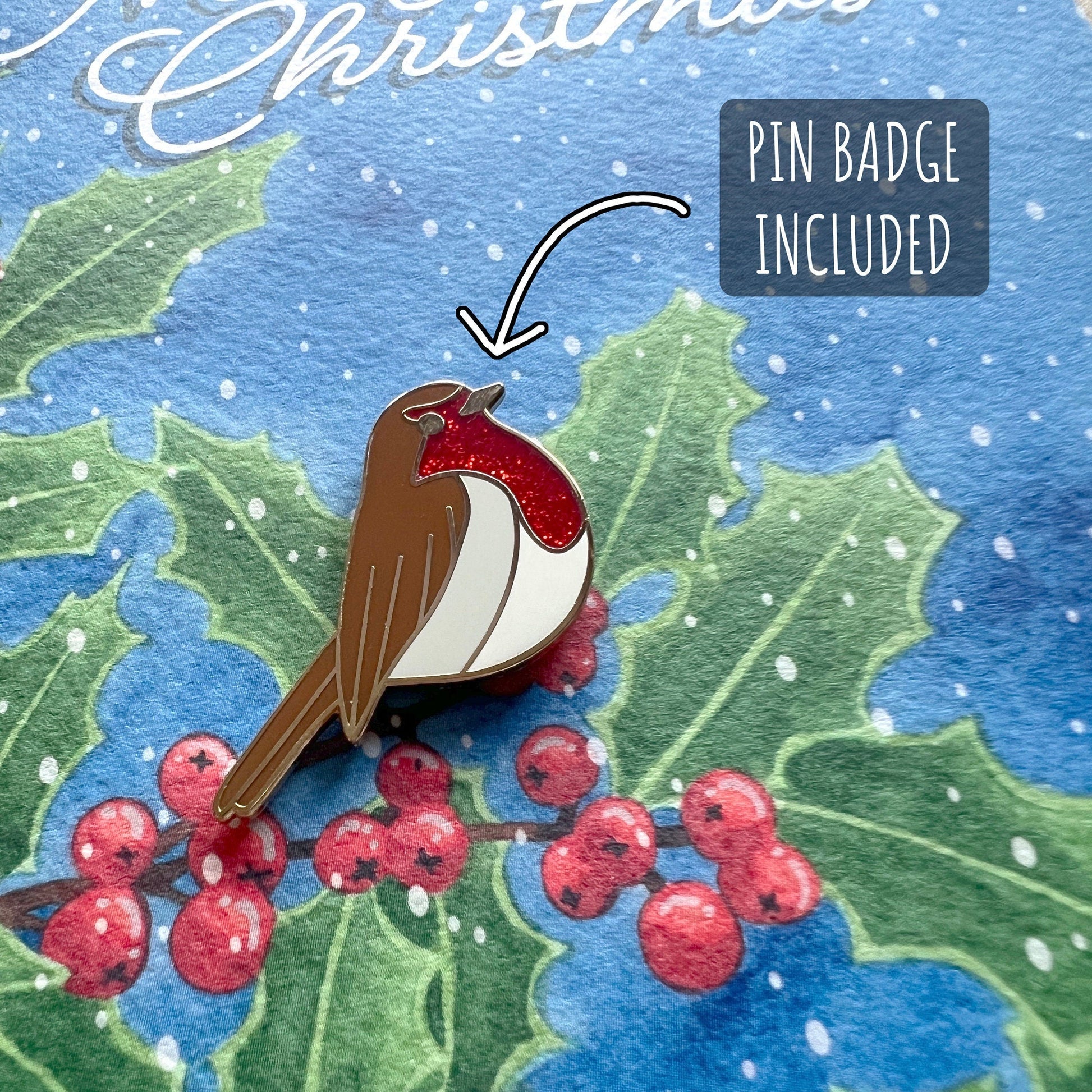 Robin Enamel Pin and Christmas Card close up showing the details of the pin badge and textures of the illustration and paper stock. with the text pin badge included. 