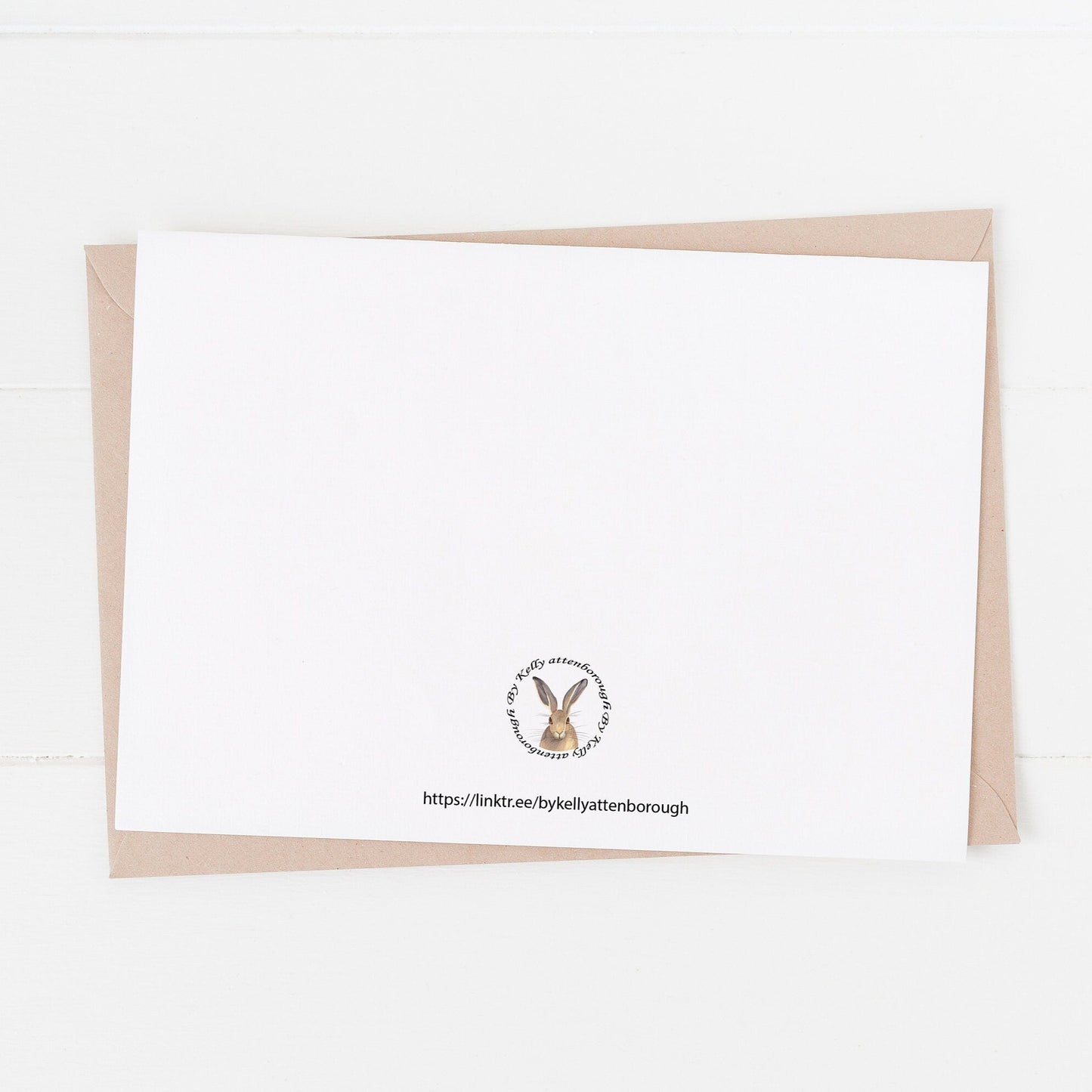 the back of the Rolling Hills Countryside Greetings Card features a brand logo and website link. laying on a white surtface.