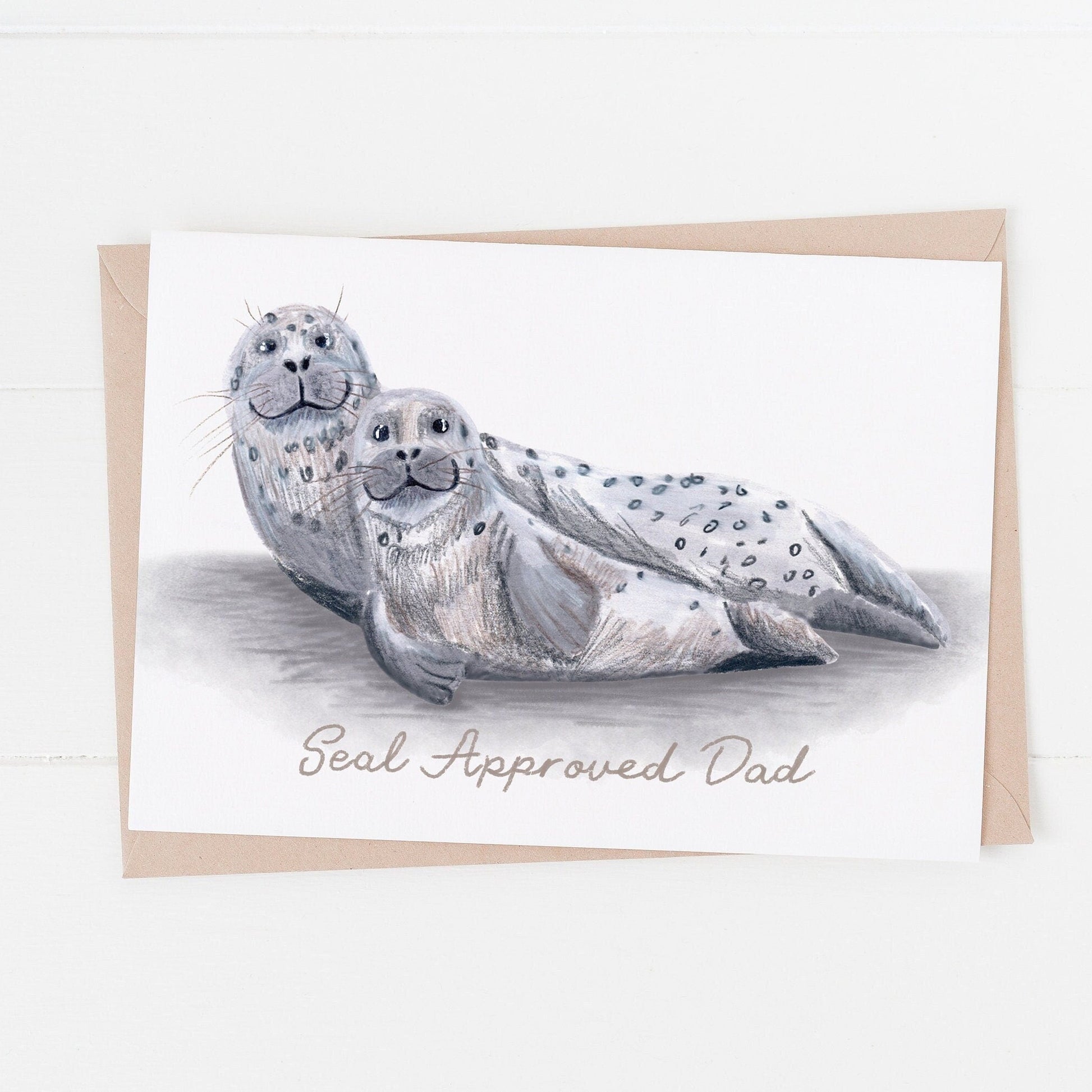 A greeting card with an illustration of a grey seal pup and an adult grey seal, with the text 'Seal Approved Dad'.