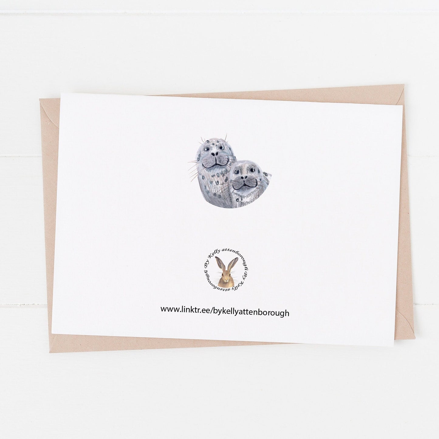 Seal Approved Dad Birthday Day Card showing the back with the brand logo and a little circle illustration of the seals faces. laying on a white surface.