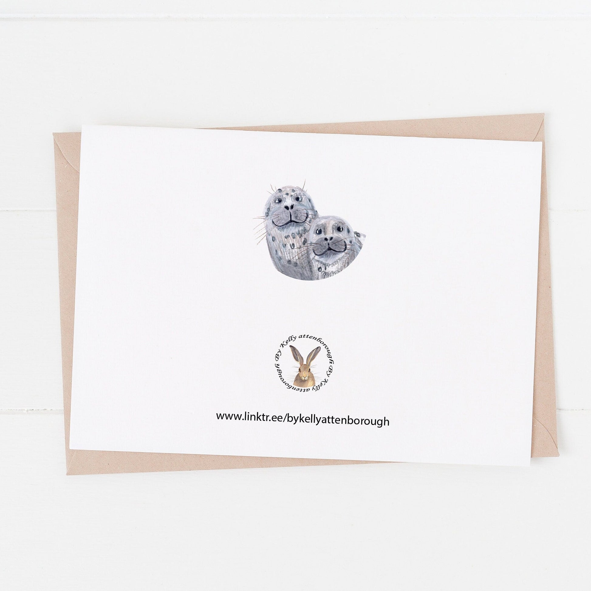 Seal Approved Dad Birthday Day Card showing the back with the brand logo and a little circle illustration of the seals faces. laying on a white surface.