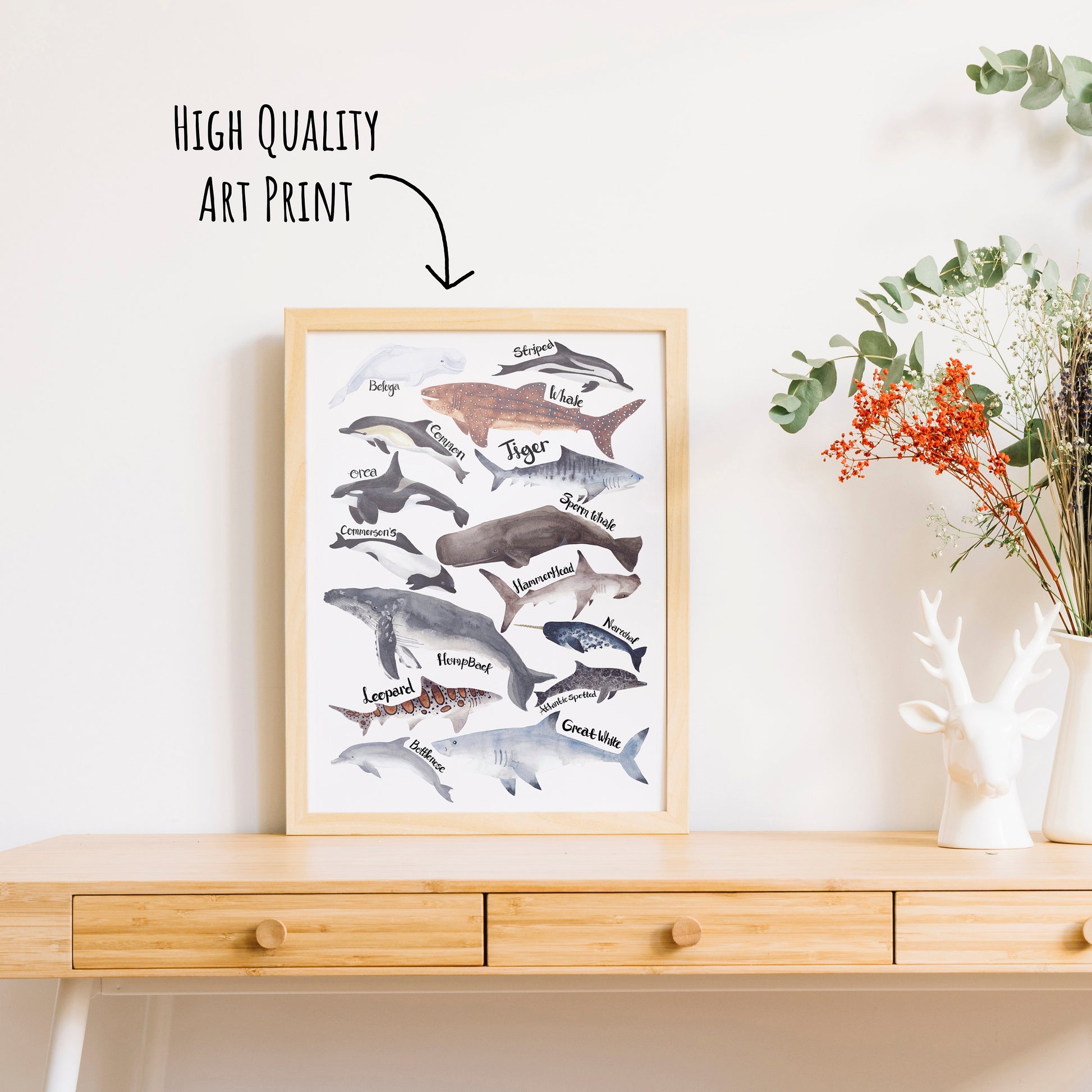 Sharks, Dolphins & Whales Art Print shown in a light wooden frame on a table top with a vase of dried foliage. (frame not included in purchase)